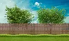 A wooden fence in a backyard with trees and a blue sky. Produktbild-Vorschau