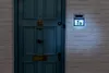 A solar-powered house number sign is mounted on a brick wall next to a blue door. Podgląd zdjęcia produktu