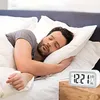A man is sleeping in bed next to a digital alarm clock. Voir les images du produit