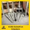 A collection of metal ground anchors and related accessories displayed on a concrete floor with a wooden and brick background. Produktbild-Vorschau