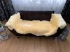 A sheepskin rug is draped over a dark brown leather sofa in a living room setting. Produktbild-Vorschau