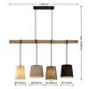 A linear pendant light fixture with a wooden beam and four fabric lampshades of different colors and sizes. Produktbild-Vorschau