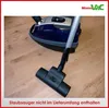 A close-up shot of a vacuum cleaner head and part of the vacuum cleaner body on a wooden floor. Produktbild-Vorschau