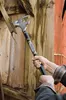 A person is using a multi-tool to pry apart wooden planks on a weathered structure. Podgląd zdjęcia produktu