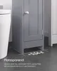 A close-up of a small, gray bathroom cabinet next to a white toilet, with text overlay indicating its space-saving design. Podgląd zdjęcia produktu