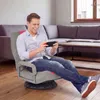 A man is playing a video game on a floor chair in a living room. Produktbild-Vorschau
