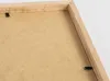 Close-up view of the back of a wooden picture frame, showing the backing board and securing clips. Anteprima dell’immagine prodotto