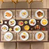 A table setting with multiple plates of food and cutlery, arranged for a meal. Produktbild-Vorschau