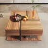 A wooden coffee table with a modern design, featuring a tray with a teapot and cups, oranges, and a vase with a plant. Voir les images du produit