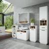 A modern bathroom with a large window overlooking a lush green forest. The bathroom features white and wood-toned furniture, including a vanity with a sink, a tall cabinet, and a smaller cabinet. Podgląd zdjęcia produktu