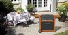 A patio setting with a table set for a meal and a barbecue grill. Produktbild-Vorschau