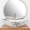 A marble basin with a gold faucet sits on a wooden vanity, with a round mirror behind it. Náhled obrázku produktu