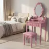 A pink vanity table with a lighted mirror and stool is set up in a bedroom next to a bed. Voir les images du produit