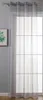 A sheer gray curtain hangs in front of a window with a grid pattern. A framed picture with green foliage is visible on the left.