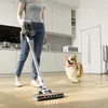 A person is vacuuming a wooden floor in a modern kitchen while a dog watches. Produktbild-Vorschau