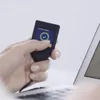A hand holding a cryptocurrency hardware wallet connected to a laptop. Produktbild-Vorschau