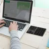 A person's hands are typing on a laptop keyboard, with a separate numeric keypad placed to the right on a wooden desk. Produktbild-Vorschau