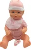 A baby doll wearing a pink hat and bib, sitting down. Produktbild-Vorschau