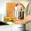A person is adding a filter to a water pitcher in a kitchen setting. Produktbild-Vorschau