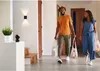 A couple is walking into a home carrying groceries. Produktbild-Vorschau