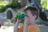 A young boy is looking through green and blue binoculars outdoors. Náhľad obrázku produktu