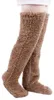 Paar braune flauschige Overknee-Socken an Beinen, vor weißem Hintergrund Náhled obrázku produktu