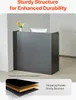 A dark gray reception desk with a computer monitor and flowers on top, set against a light gray wall. Anteprima dell’immagine prodotto