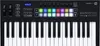 A top-down view of a black MIDI keyboard with white keys and colorful illuminated pads. Náhľad obrázku produktu