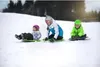Three children are sledding down a snowy hill. Produktbild-Vorschau