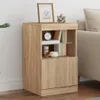 A wooden bedside table with books and decorative items on it, placed next to a sofa. Produktbild-Vorschau