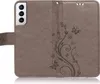 A close-up view of a brown flip phone case with a floral and butterfly embossed pattern. Produktbild-Vorschau