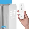 A hand holding a remote control in front of a white electric heater with a digital display. Produktbild-Vorschau