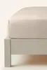 A close-up view of a beige fitted sheet on a bed frame. Podgląd zdjęcia produktu