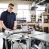 A man is using a table saw in a workshop. Podgląd zdjęcia produktu