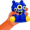 A hand is squeezing a blue stress toy monster. Voir les images du produit