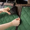 A close-up shot of hands zipping up a green quilted car seat cover. Náhľad obrázku produktu