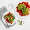 Two plates of food, a glass of water, and a napkin on a white surface. Anteprima dell’immagine prodotto