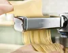 Hands are using a Kenwood pasta maker to create fettuccine noodles from a sheet of dough. Produktbild-Vorschau