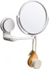 A white makeup mirror with a suction cup mount and a wooden facial brush hanging from it. Produktbild-Vorschau