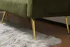 A close-up view of the bottom of a green sofa with gold legs, resting on a fluffy gray rug. Produktbild-Vorschau