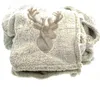 A folded beige blanket with a deer head applique. Produktbild-Vorschau