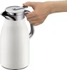 A hand is holding a white insulated carafe with a silver lid and handle. Anteprima dell’immagine prodotto