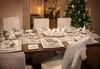 A dining table set for a Christmas meal with a decorated Christmas tree in the background. Produktbild-Vorschau