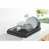 A dark gray dish drying rack filled with dishes and cutlery, placed on a white countertop next to a sink. Podgląd zdjęcia produktu