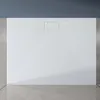 A white shower tray with a textured surface and a central drain cover, set against a gray wall and floor. Anteprima dell’immagine prodotto