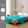 A bed with a turquoise comforter spread over it, with pillows and a bedside table. The left side of the image shows available sizes. Náhled obrázku produktu