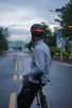 A person wearing a black helmet with LED lights is sitting on a yellow bicycle on a road. Náhled obrázku produktu