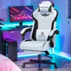 A white and black gaming chair is shown in a room with a computer desk and monitor. Podgląd zdjęcia produktu