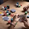 A game of poker being played on a wooden table with chips, cards, and dice. Podgląd zdjęcia produktu