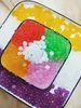 A top-down view of a colorful assortment of popping boba pearls arranged in a square dish and on a larger rectangular plate. Produktbild-Vorschau